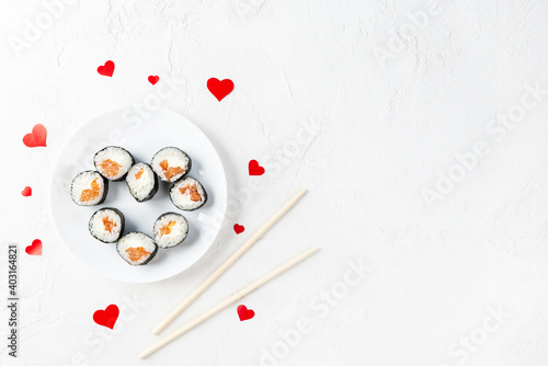 Sushi rolls for Valentine's Day with red hearts on a white plate. Horizontal orientation, copy space, top view.
