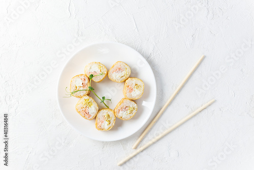 Sushi rolls in a white plate with chopsticks.
