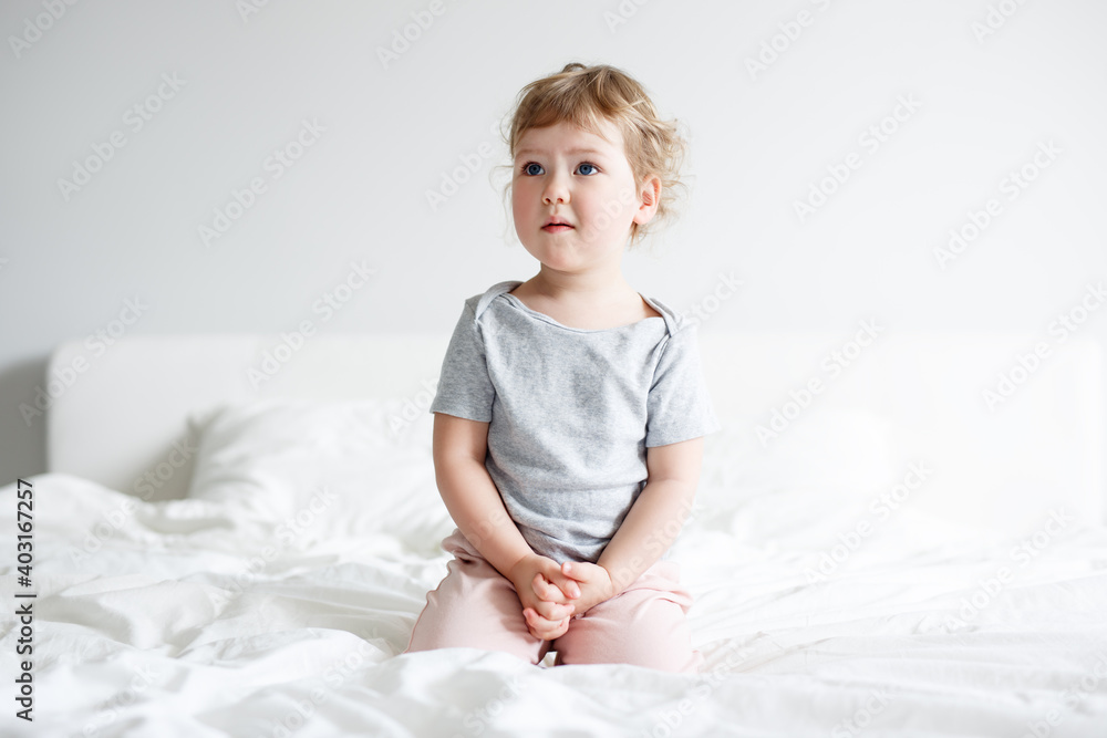 cute little girl sitting on bed and dreaming or thinking about something cute little girl sitting on bed and dreaming or thinking about something