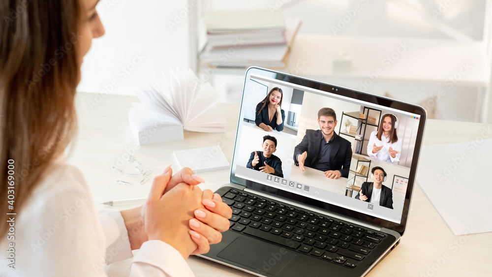Video call. Virtual meeting. Online teamwork. Pandemic WFH. Ambitious diverse multiracial team greeting new employee on laptop screen at light modern home office. - obrazy, fototapety, plakaty 