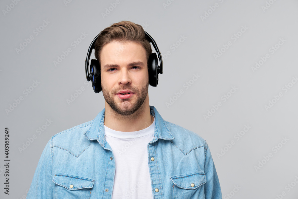Close up portrait of cheerful young man enjoying listening to music wearing casual jeans outfit - obrazy, fototapety, plakaty 