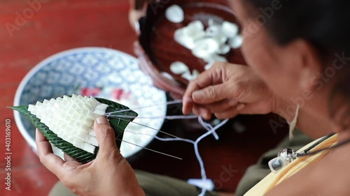 Old woman is made a hundred flowers or wreathe by hand on tradditional culture of Thailand. photo