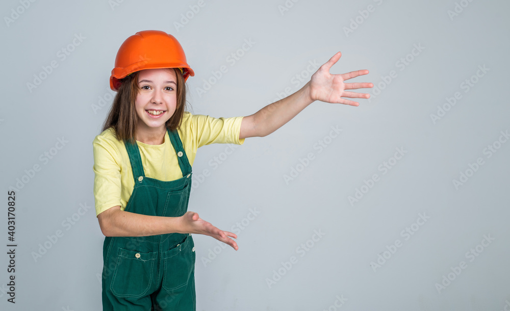 girl kid in hard hat on construction site, presenting product, copy space for advertisement girl kid in hard hat on construction site, presenting product, copy space for advertisement