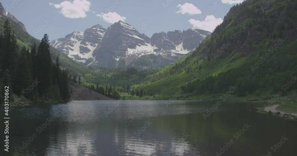 Scenic timelapse view of Rocky mountains and a lake in sunny summer day with cloud shadows passing by Scenic timelapse view of Rocky mountains and a lake in sunny summer day with cloud shadows passing by