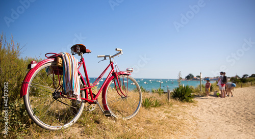 Vieux vélo rouge au bord de la plage en France.