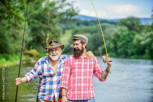 Family time. Activity and hobby. Fishing freshwater lake pond river. Fisherman with fishing rod. Bearded men catching fish. Mature man with friend fishing. Summer vacation. Happy cheerful people