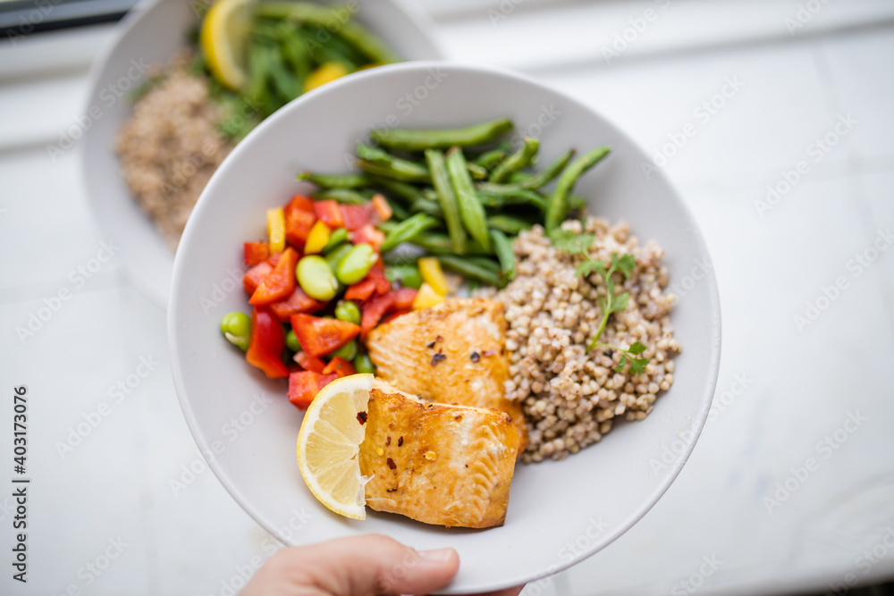 Hand holding salmon and buckwheat dish with green beans Hand holding salmon and buckwheat dish with green beans