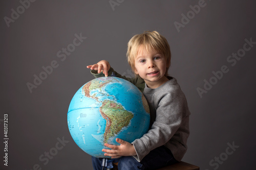 Cute toddler child, boy, hugging big globe, isolated image
