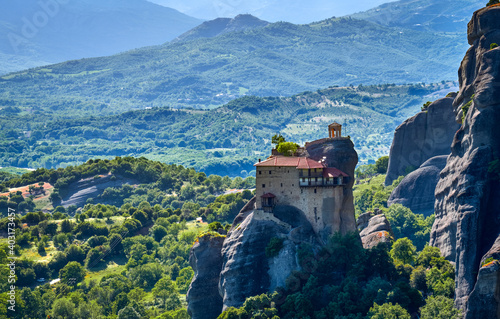 Close view of monastery of St Nicholaos Anapafsas on top of sedimentary pillar, green hills of Meteora valley at midday. Greece, UNESCO World Heritage photo
