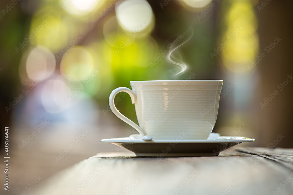 Fototapeta premium cup of coffee on wood chair with nature view behind