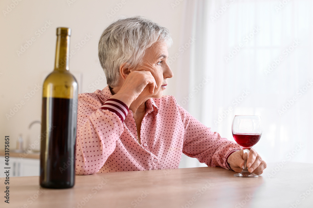 Stressed senior woman drinking wine at home - obrazy, fototapety, plakaty 