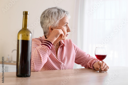 Stressed senior woman drink...