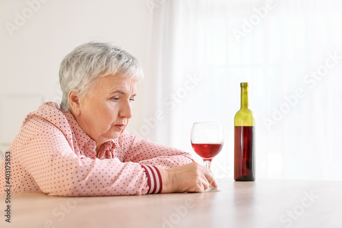 Stressed senior woman drink...