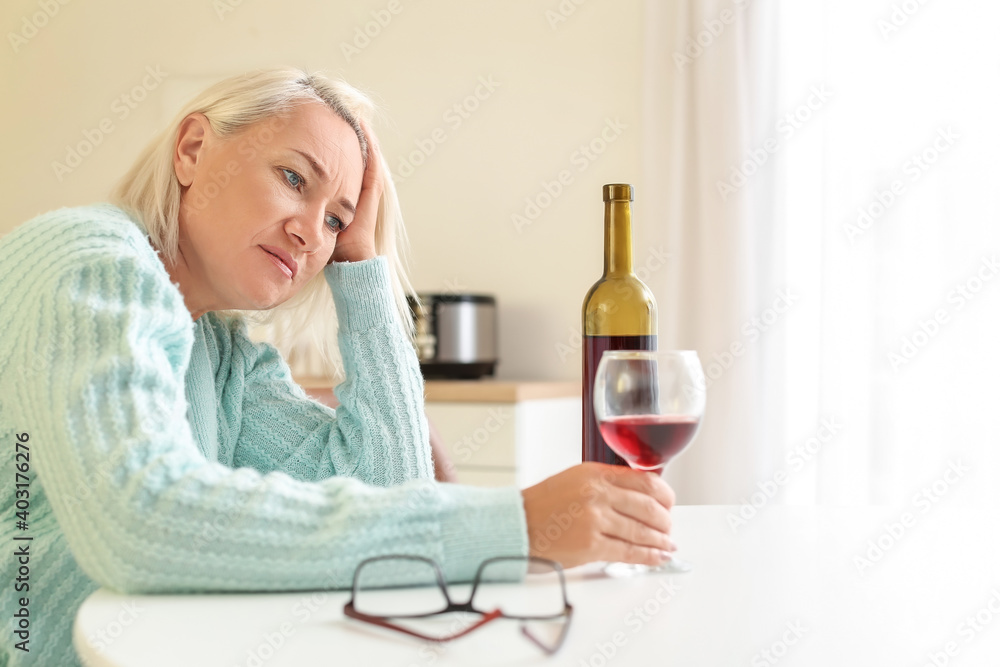 Stressed mature woman drinking wine at home Stressed mature woman drinking wine at home