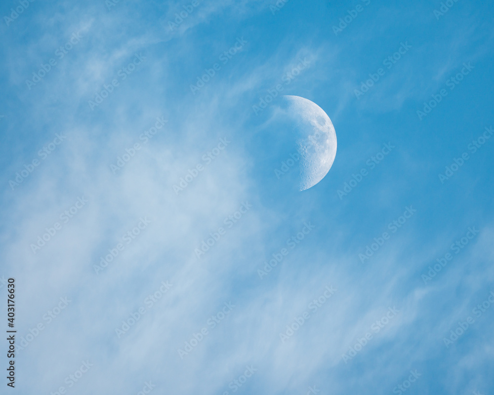 Moon among white clouds in blue sky