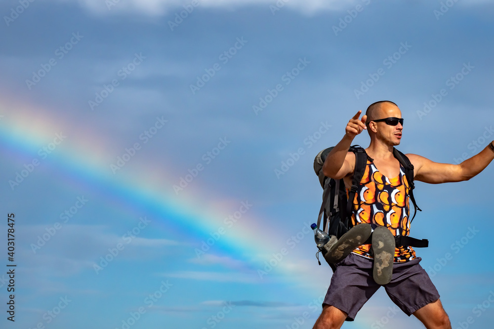 Male hiker hiking with rainbow in background
