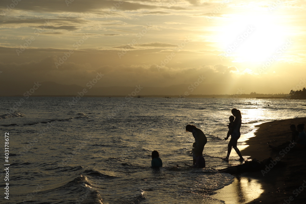 silhouette of a family enjoying the beach in sunset background