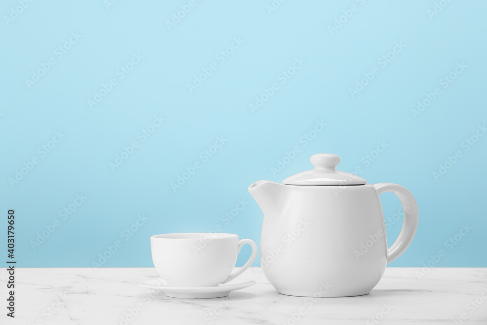 Teapot and cup on table against color background Teapot and cup on table against color background