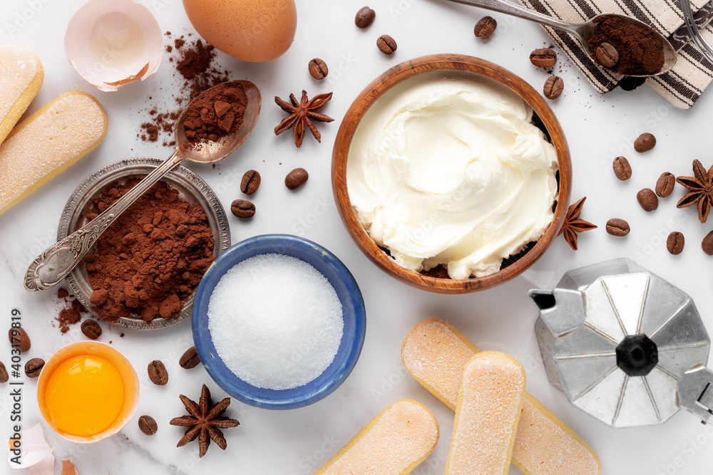 Italian dessert Tiramisu cake ingredients overhead view against white marble background Italian dessert Tiramisu cake ingredients overhead view against white marble background