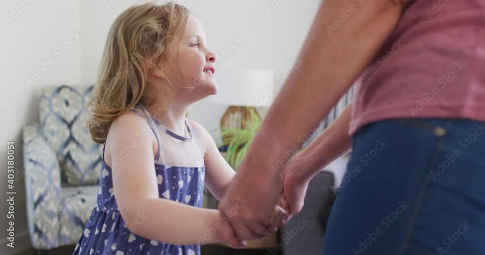 Caucasian mother and daughter having fun dancing in living room Caucasian mother and daughter having fun dancing in living room