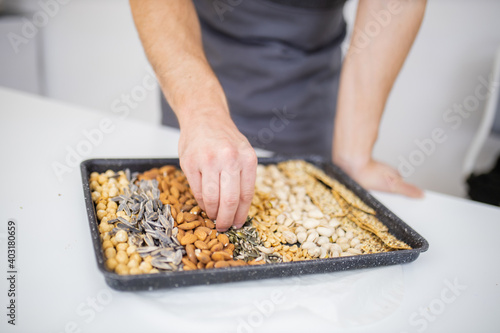 Male hand picking seeds from a black tray with seeds and nuts