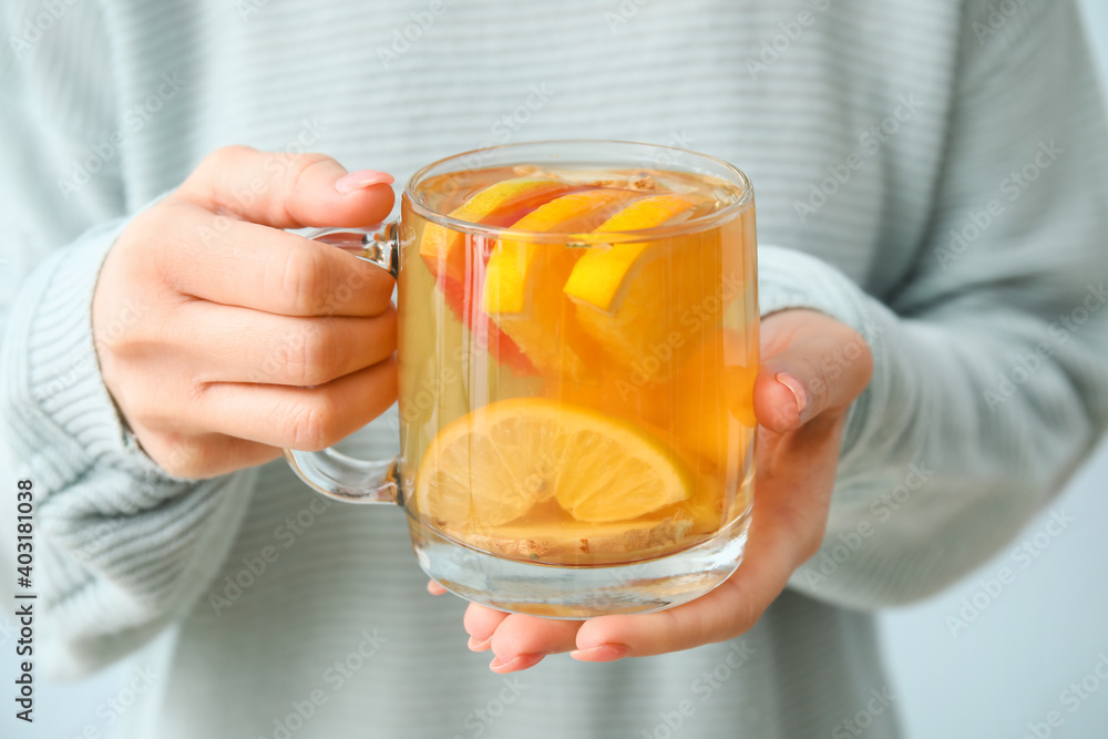 Woman holding cup of tea with lemon and ginger, closeup Woman holding cup of tea with lemon and ginger, closeup