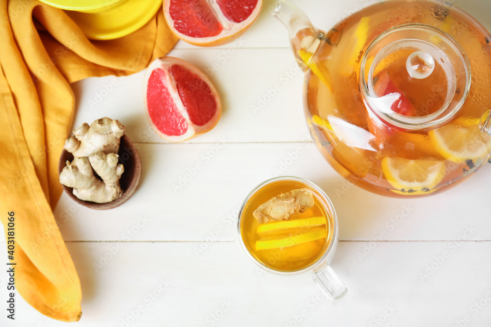 Teapot and cup of healthy drink with lemon and ginger on table Teapot and cup of healthy drink with lemon and ginger on table