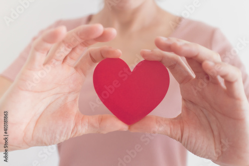 Woman in pink dress shows heart shape in the concept of love and valentine.