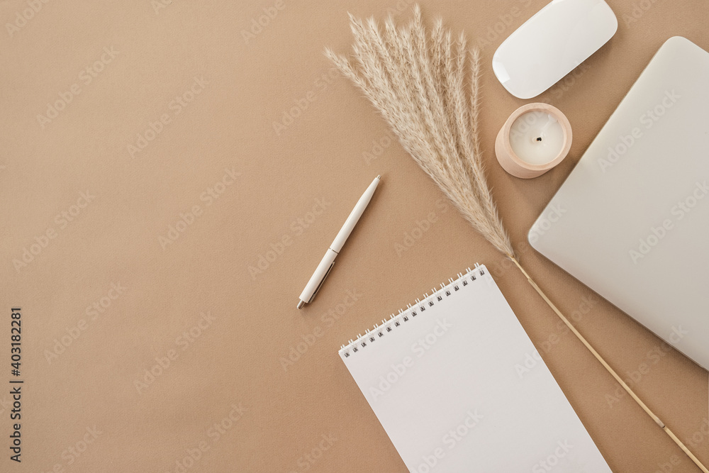 Flatlay of spiral flip notebook with blank paper sheet. Laptop, pampas grass, stationery on beige peachy pastel background table. Minimalist home office desk workspace. Top view mockup copy space. - obrazy, fototapety, plakaty 