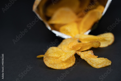 Opened bag of chips on black background, copy space