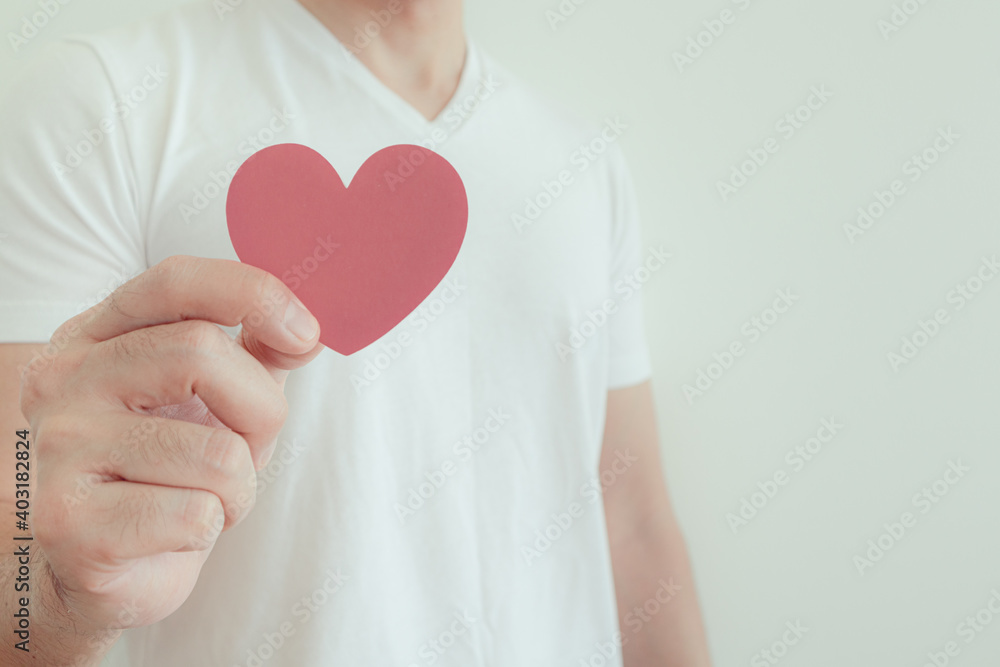 Man in white t-shirt shows pink heart shape in concept of love and Valentine. Man in white t-shirt shows pink heart shape in concept of love and Valentine.