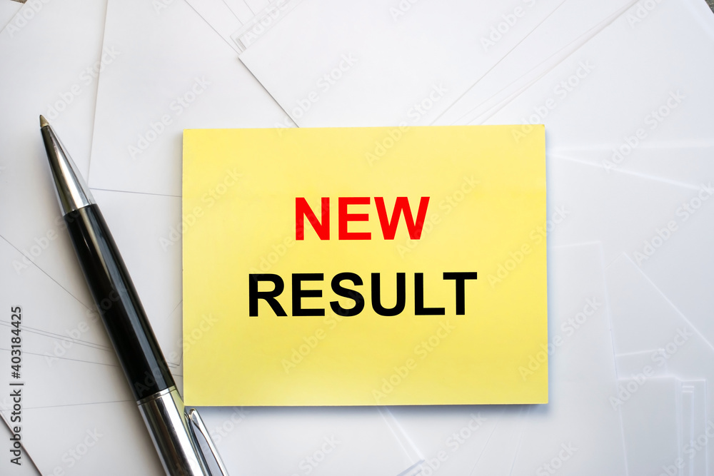Near the pen on a stack of white sheets of paper is a yellow sheet on which the inscription new result. Concept photo Near the pen on a stack of white sheets of paper is a yellow sheet on which the inscription new result. Concept photo