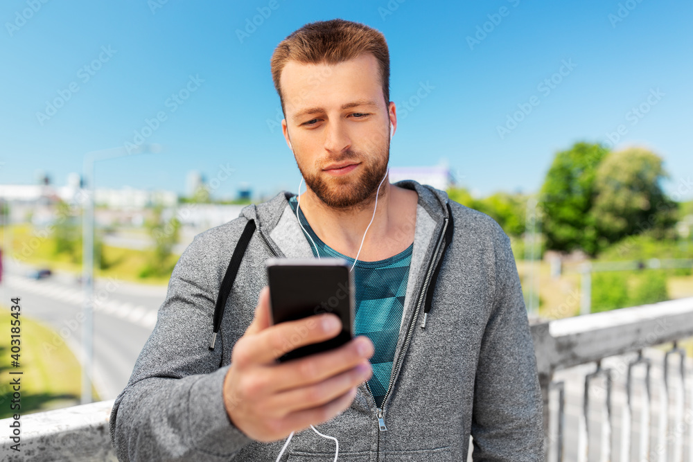 fitness, sport and technology concept - young man with earphones and smartphone listening to music outdoors fitness, sport and technology concept - young man with earphones and smartphone listening to music outdoors