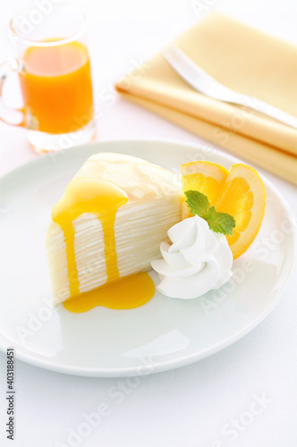 Homemade cheese crepe cake with orange sauce on table, vertical view.