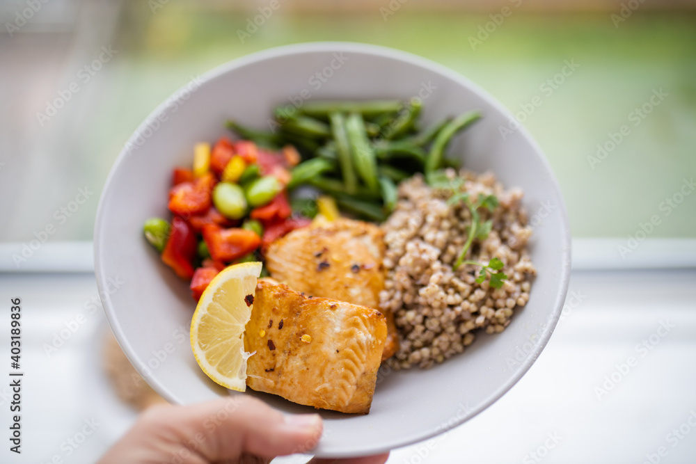 Hand holding salmon and buckwheat dish with green beans Hand holding salmon and buckwheat dish with green beans