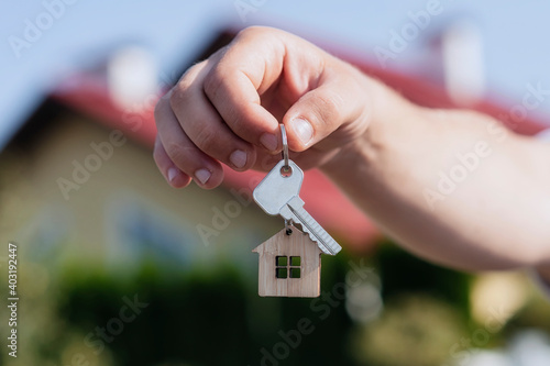 Man holds the keys to the house in his hands against the backdrop of residential buildings. Concept for buying and renting apartments.