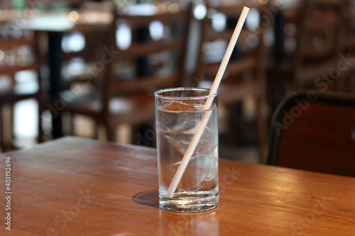 Fresh water in glass with paper drinking straw on restaurant background. Concept for reduce plastic pollution and support green eco friendly products.