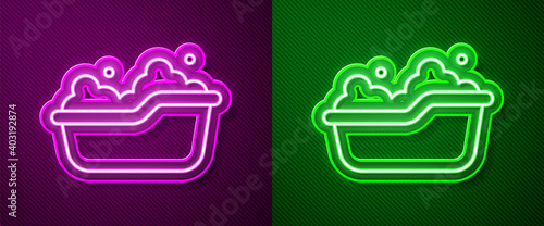 Glowing neon line Baby bathtub with foam bubbles inside icon isolated on purple and green background. Vector.