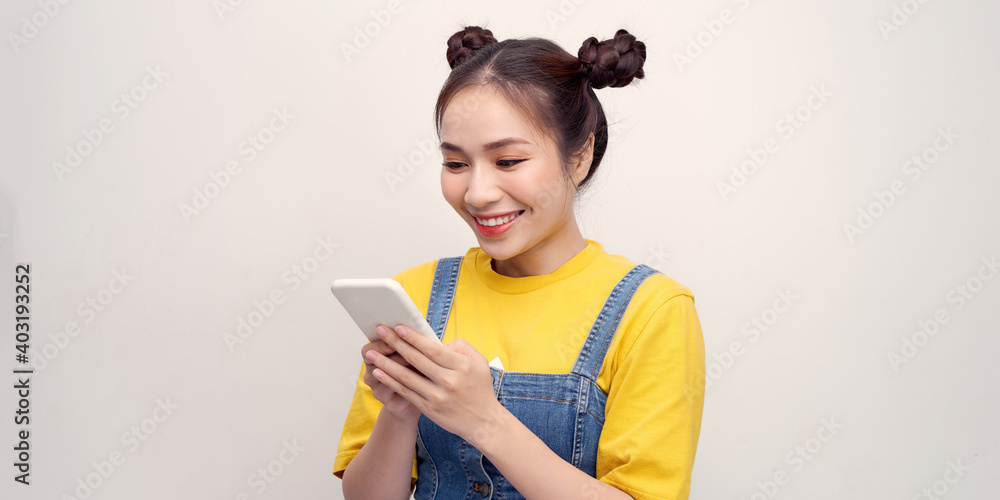 Excited beautiful woman receiving SMS in mobile phone over plain background Excited beautiful woman receiving SMS in mobile phone over plain background