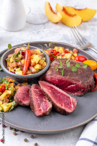 Fried beef steak with peach fruit salsa, tomato and chili.