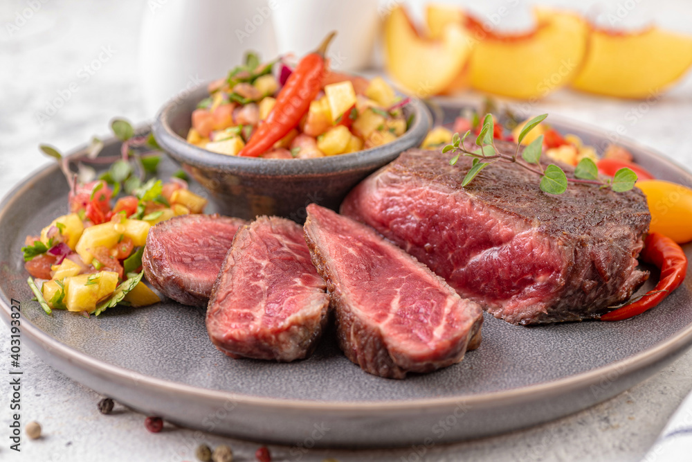 Fried beef steak with peach fruit salsa, tomato and chili.