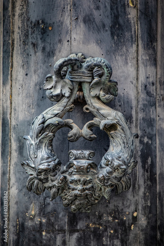 Door handle and door knocker against wooden texture in Venice, italy. 