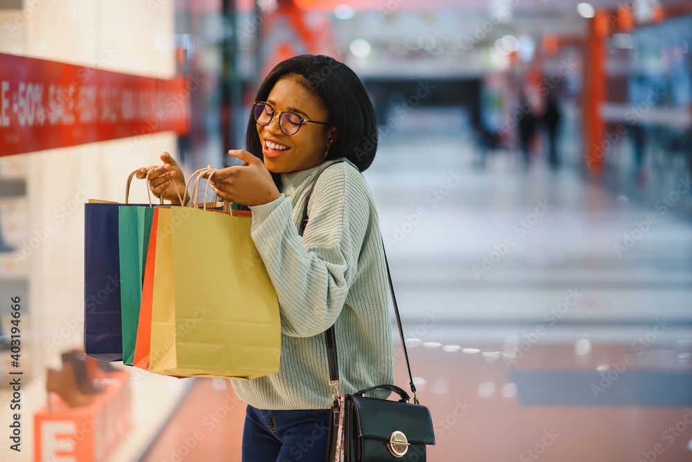 Beautiful african american woman holding multicolored shopping bags in a store.
