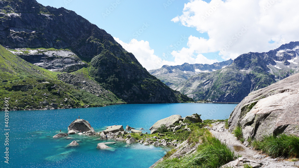 Landschaft am Gelmersee in der Schweiz. Rundwanderung an einem sonnigen Tag um den Gelmer See mit türkisblauem Wasser und Bergen im Hintergrund..