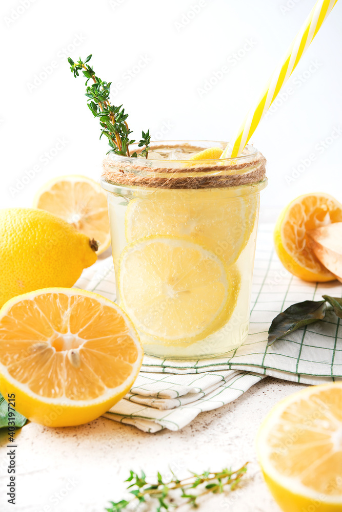 Fototapeta premium Homemade refreshing lemonade, detox drink with lemon and herbs on a light background