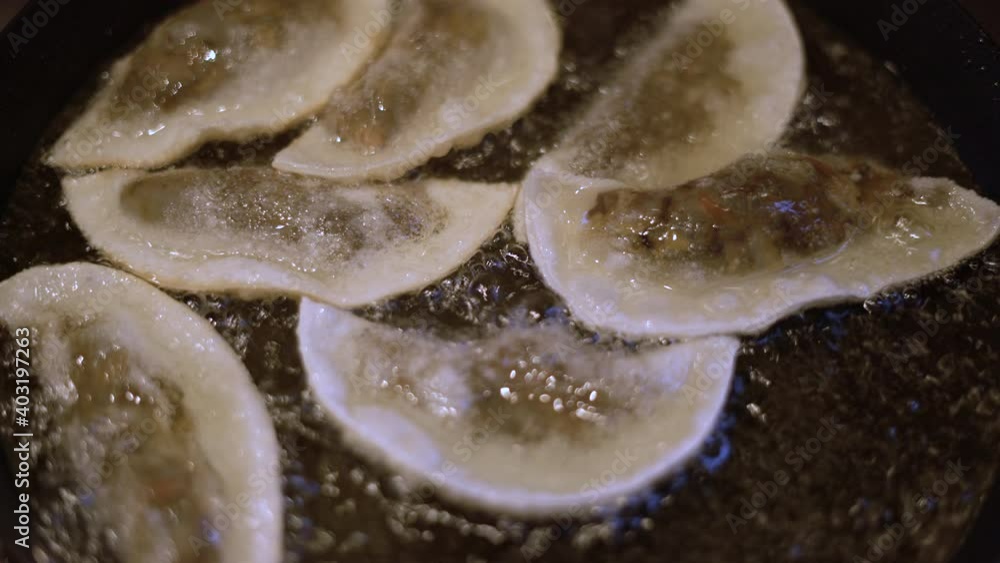 Gyoza dumplings with mushroom filling frying in hot pan. Golden crunchy dumplings cooking in oil. Gyoza dumplings with mushroom filling frying in hot pan. Golden crunchy dumplings cooking in oil.