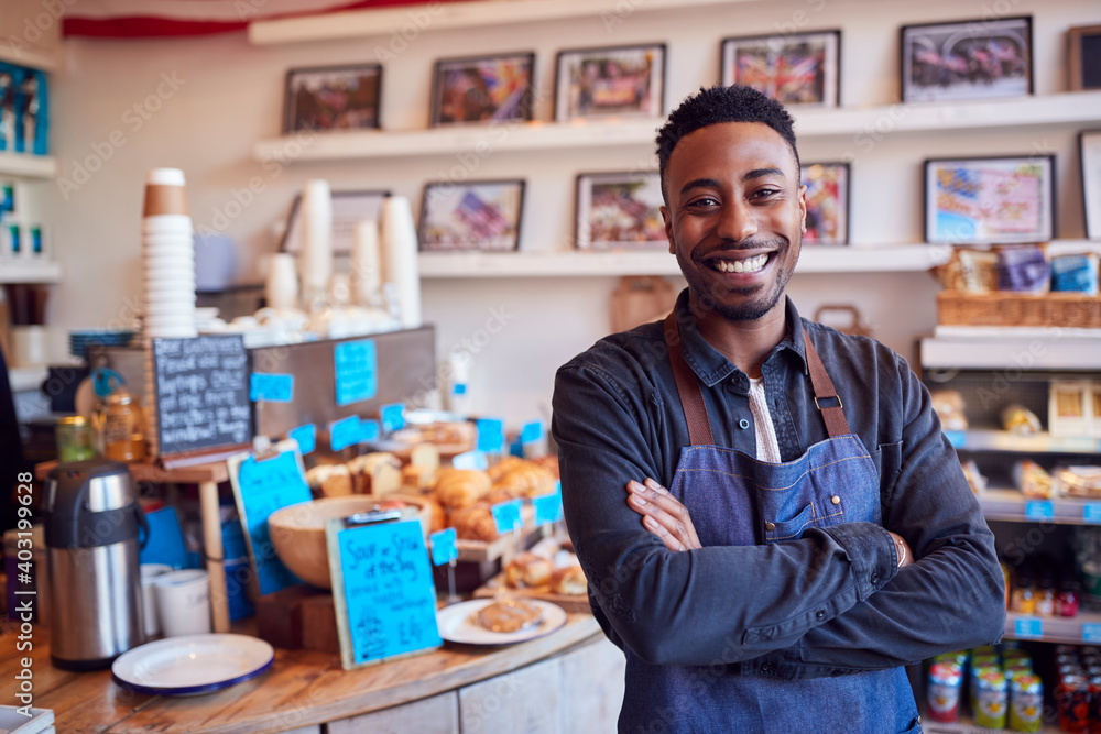 Portrait Of Smiling Male Owner Of Coffee Shop Standing By Counter Portrait Of Smiling Male Owner Of Coffee Shop Standing By Counter