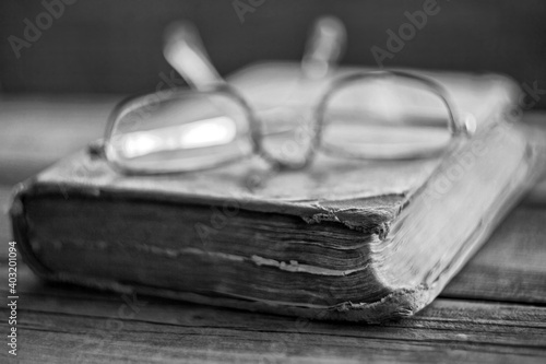 Vintage glasses lying on blurred, shabby battered old book photo