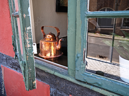 Copper tea pot kettle in a window of an old house photo