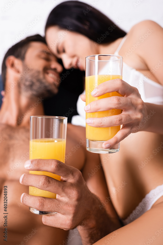 close up view of glasses with juice in hands of smiling young couple on blurred background close up view of glasses with juice in hands of smiling young couple on blurred background